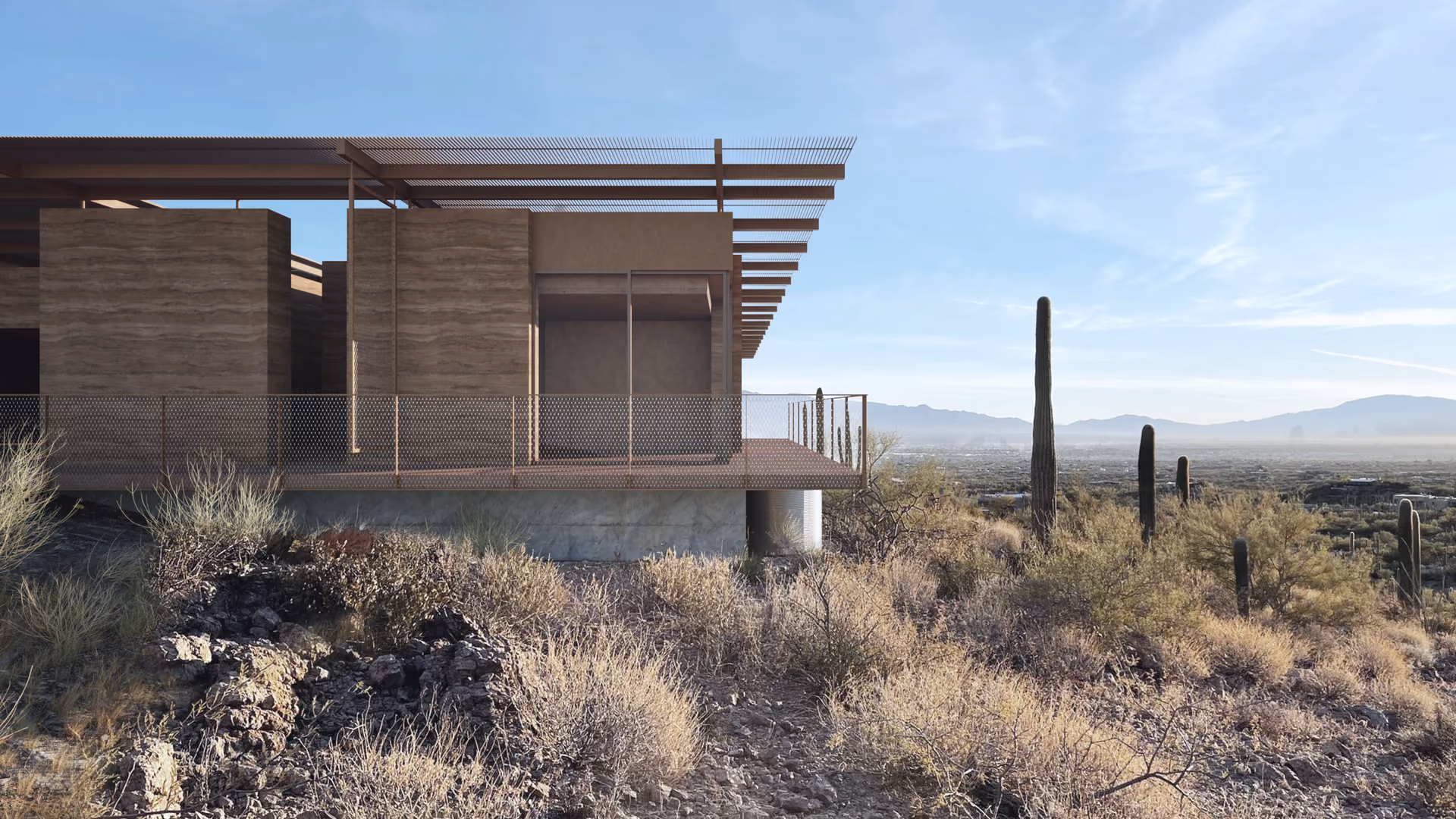 A house of rammed-earth walls under a steel canopy above the desert